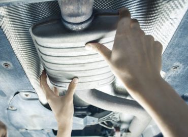 muffler being placed on the underside of a car